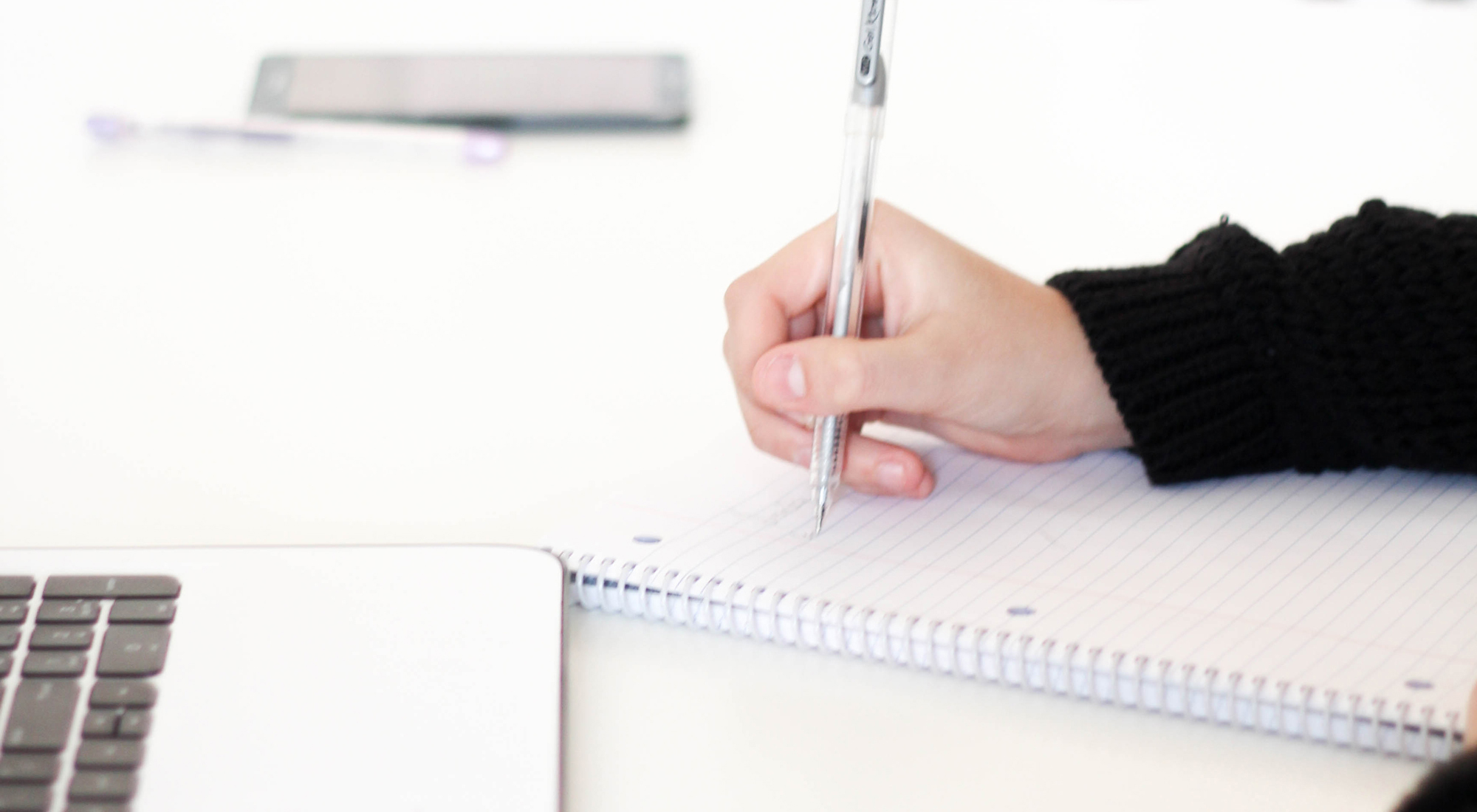 close-up image of a hand holding a pen over a notebook