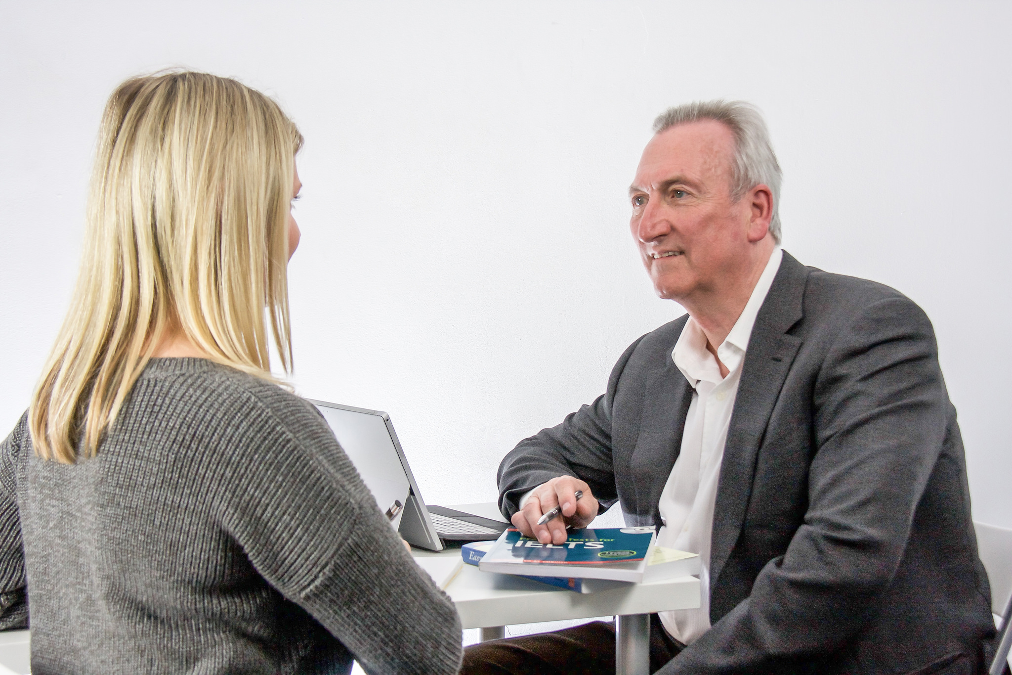 Mike and a student sitting at a table facing each other working on communication skills